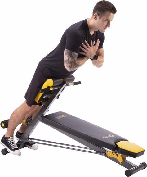 Multifunksjonell Treningsbenk i sort og gult, sett fra siden med mann som trener, polstrede puter og skrå ryggstøtte.