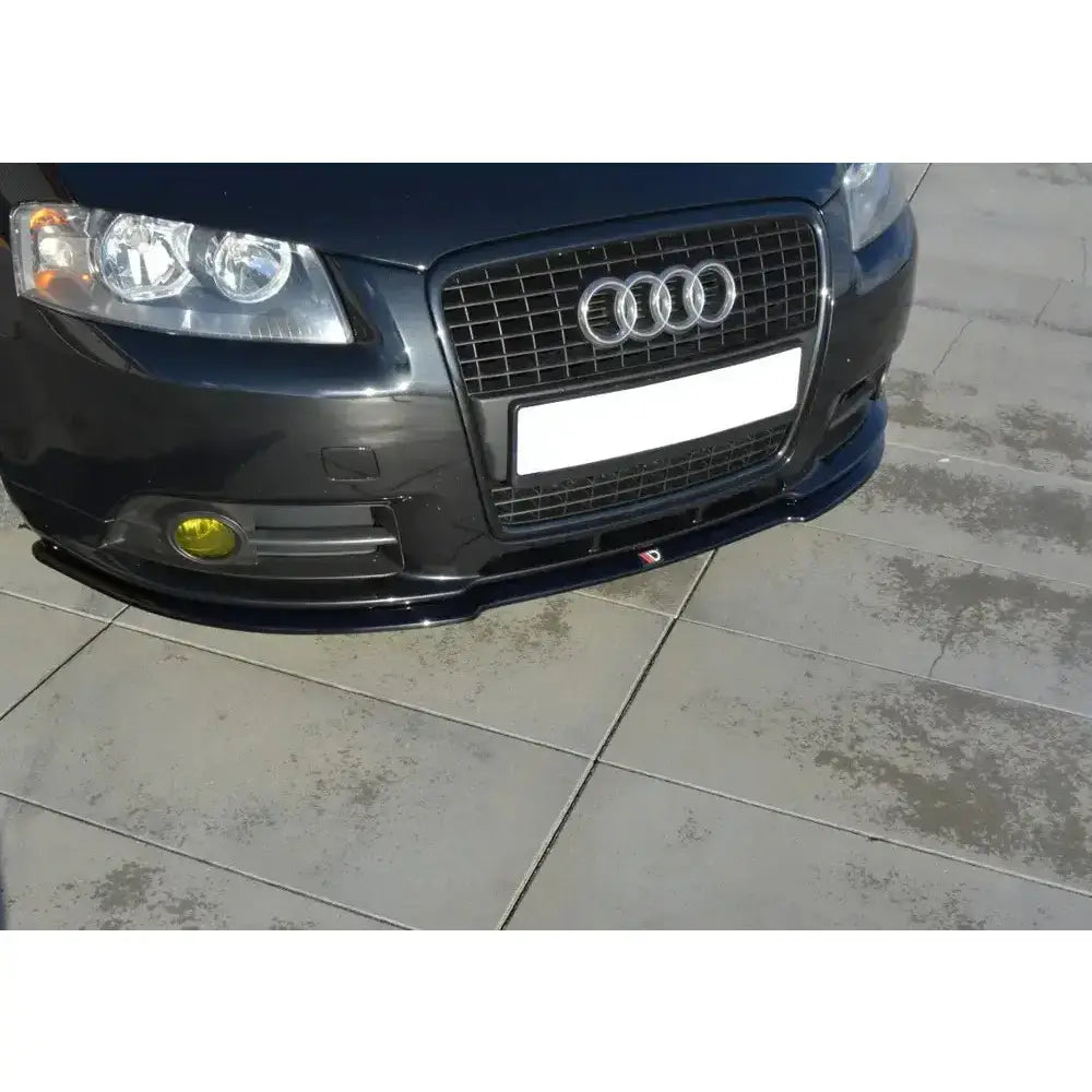 Frontleppe Audi A3 8P S-Line montert på mørk bil med gule tåkelys og sort grill, sett skrått forfra.