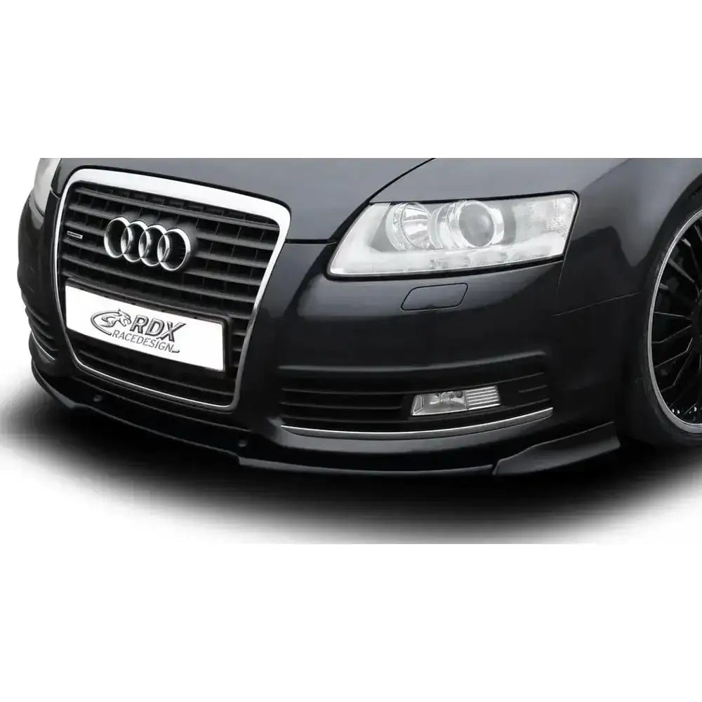 Frontleppe Audi A6 4F 08-11 i sort plast montert foran på bilfanger, sett skrått forfra.