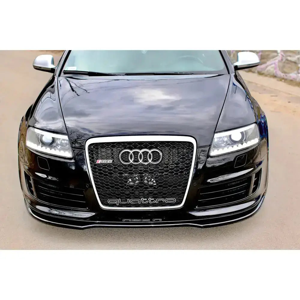Frontspoiler Audi Rs6 C6 i sort med skinnende overflate, Audi-logo og quattro-grill sett forfra.