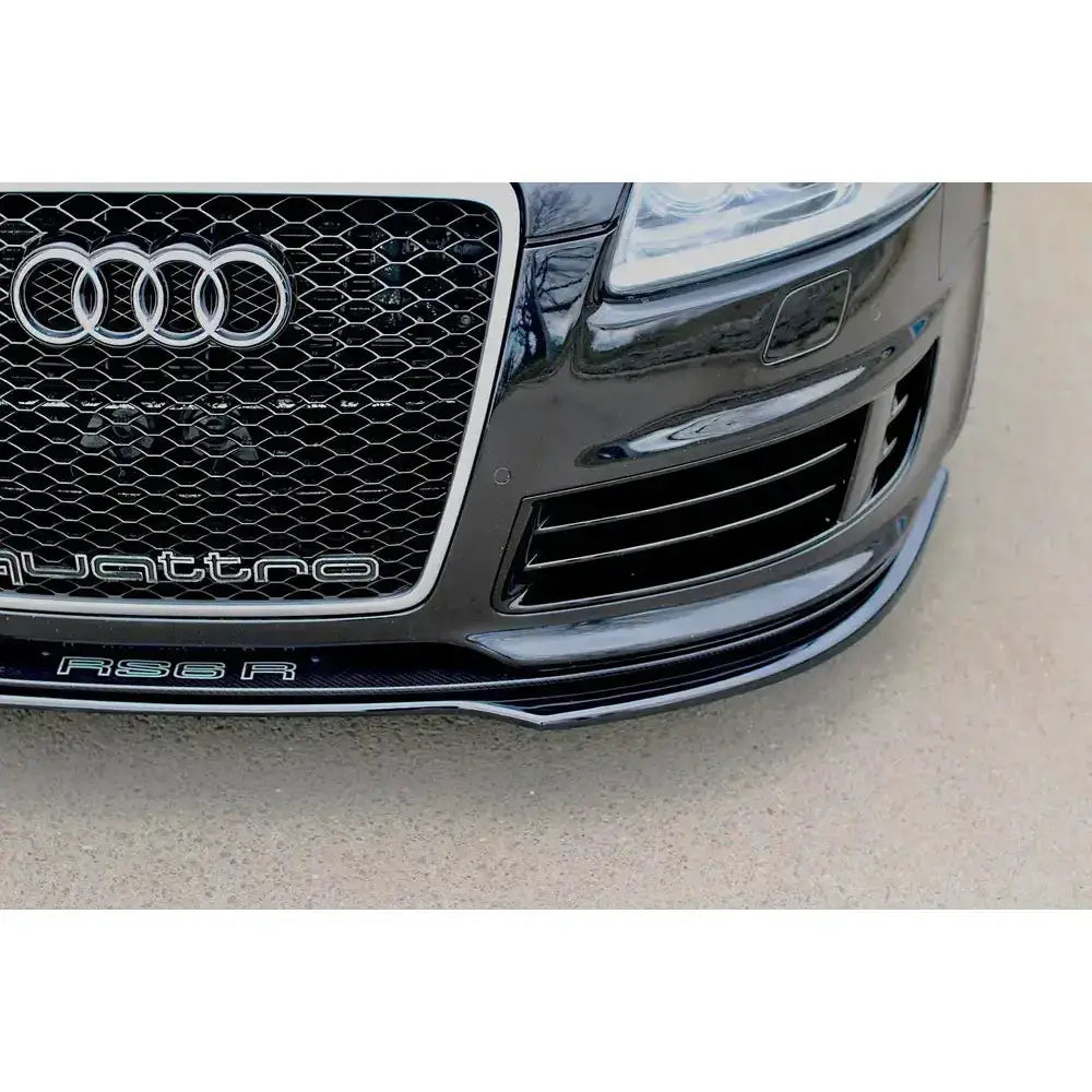 Frontsplitter Audi Rs6 C6 med sort grill, quattro-logo og detaljer i blankt metall og karbon.