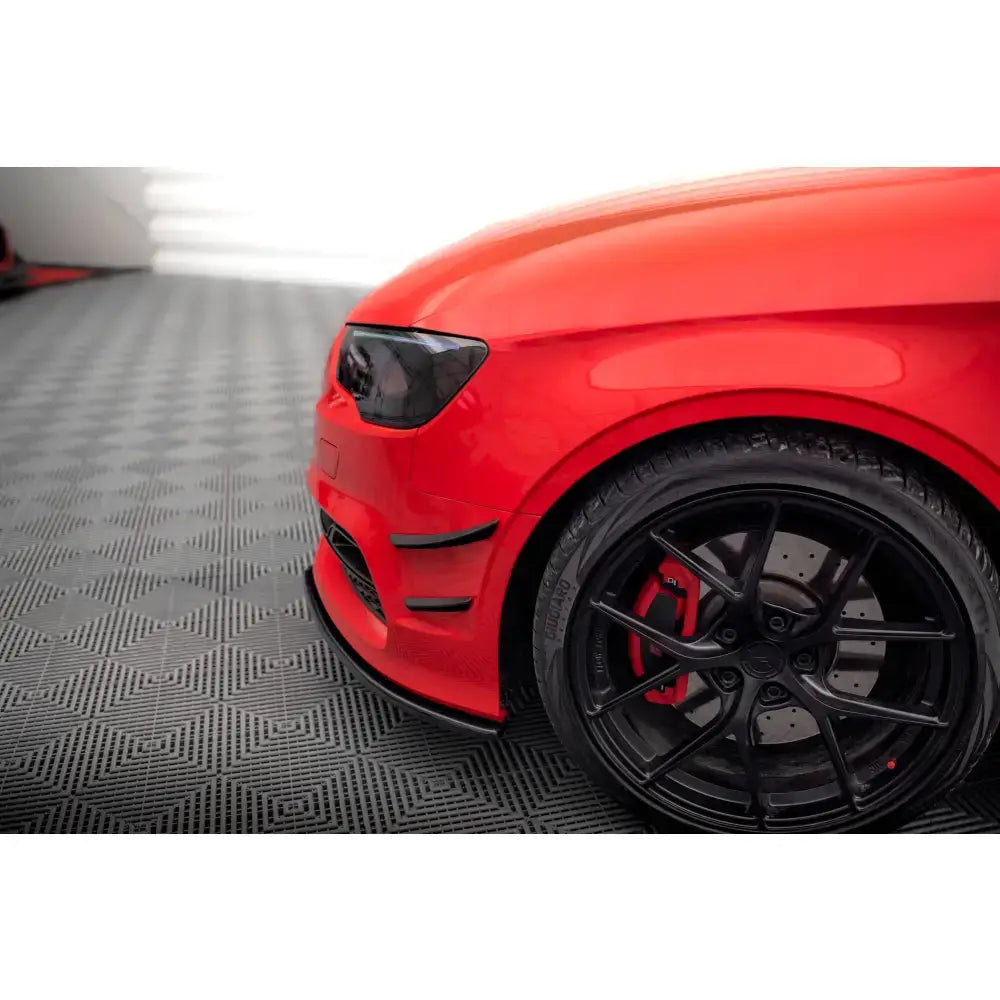 Front lip av Audi S3 med sorte felger og synlig bremseskive, sett fra siden på grått gulv.