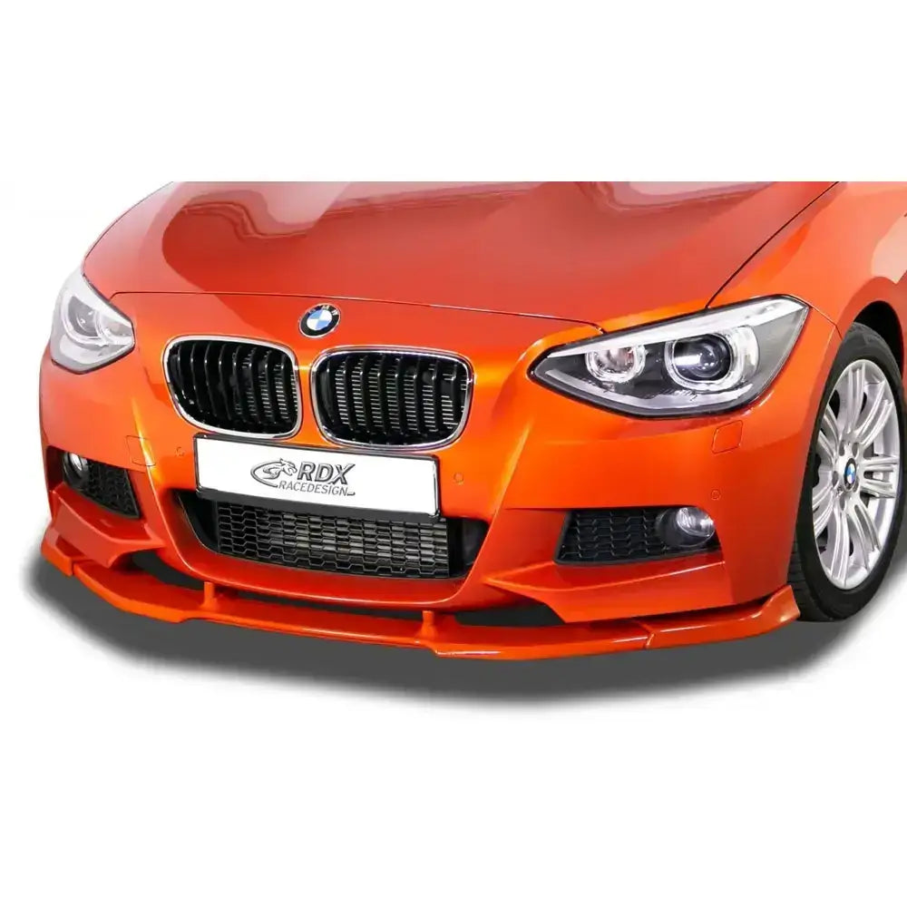 Frontleppe BMW 1 F20/F21 11-15 M-Tech montert på oransje bil med svarte grilldetaljer.