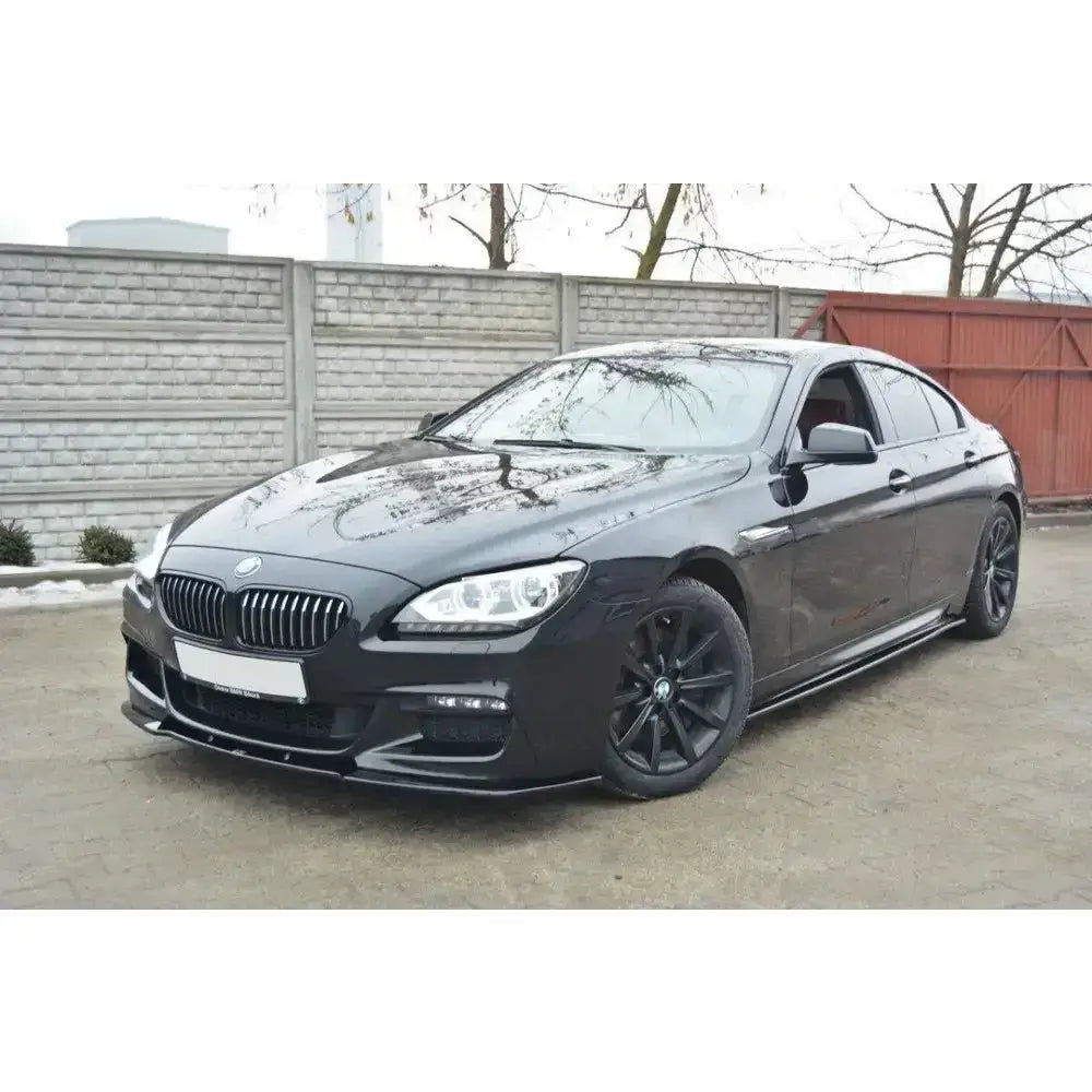 Front lip på BMW 6 Gran Coupé Mpack med svarte felger, sportslige detaljer og murvegg i bakgrunnen.