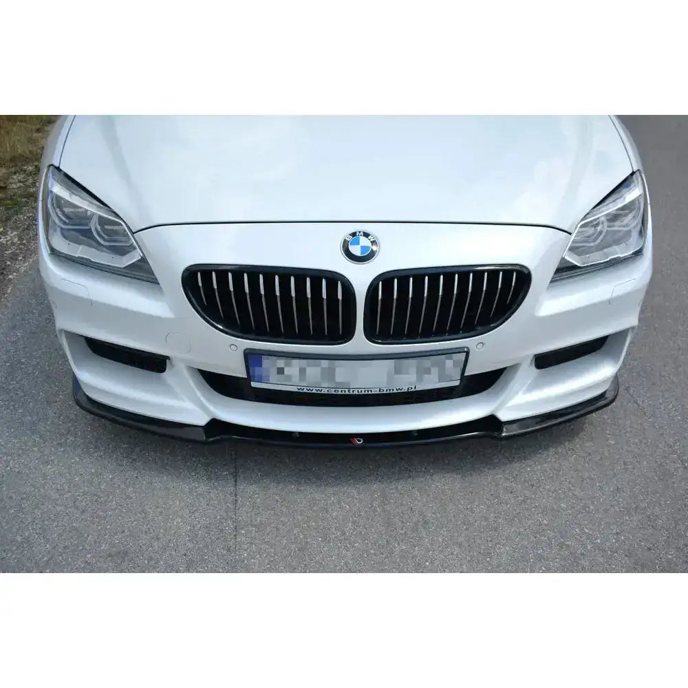 Front splitter til BMW 6 Gran Coupé Mpack, sort spoiler montert på hvit bil parkert på asfalt.