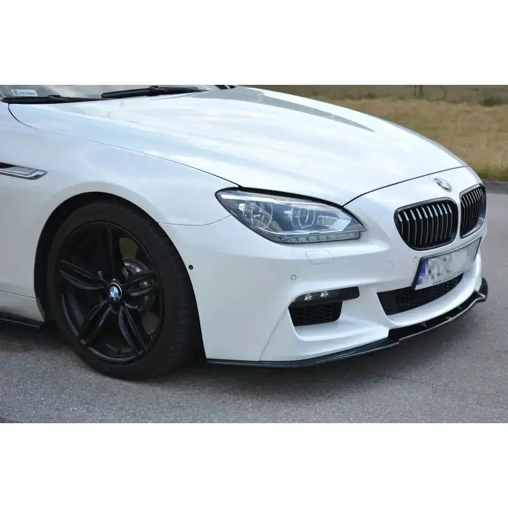 Frontspoiler til BMW 6 Gran Coupé Mpack, nærbilde av hvit bil med svart splitter og sorte felger.