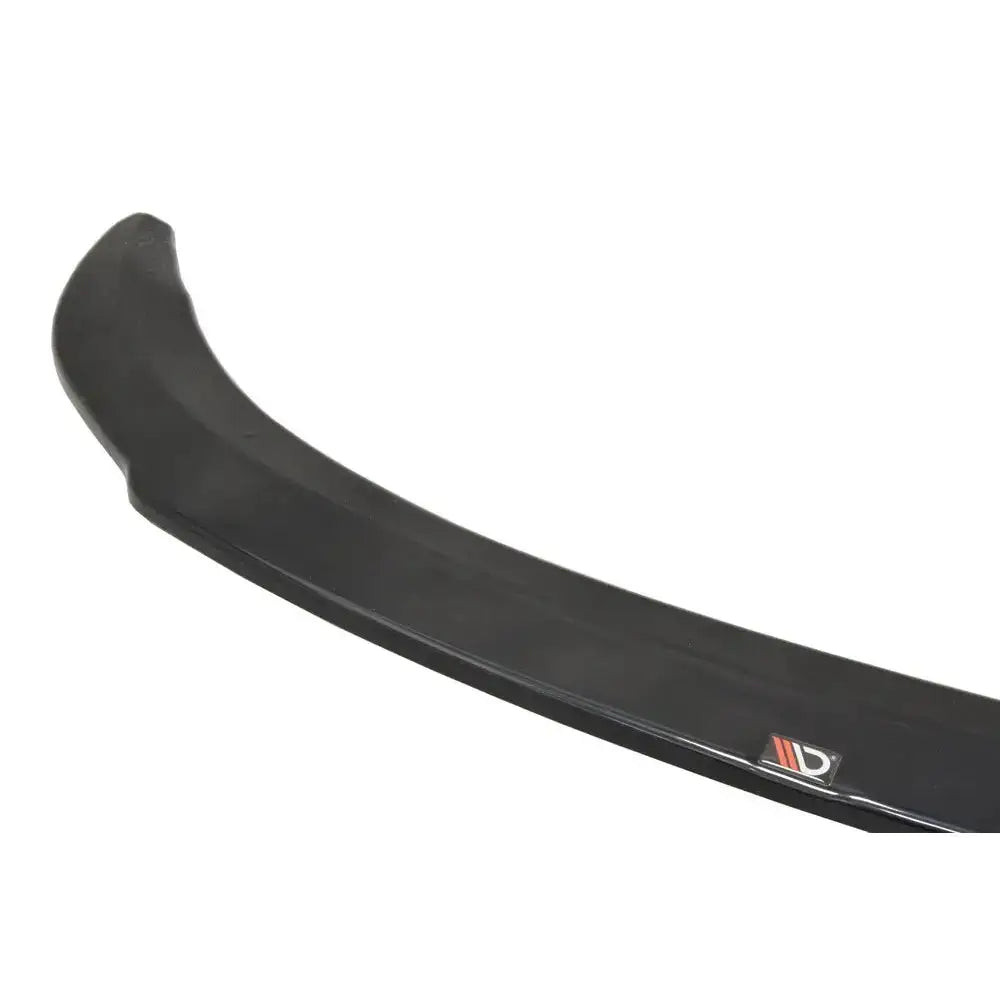 Frontspoiler Bmw M4 F82 M-Performance i sort plast, vist fra skrå vinkel med logo på hvit bakgrunn.