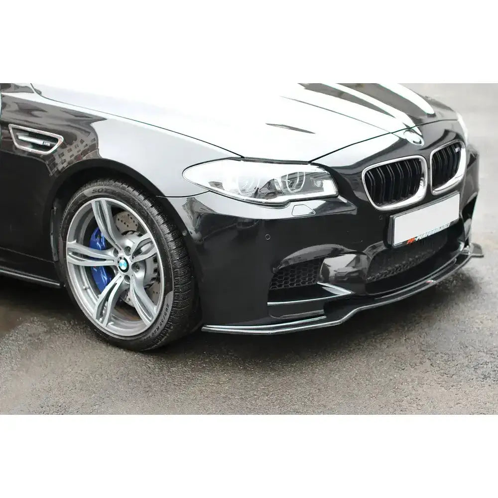 Frontleppe Bmw M5 F10/F11 i blank sort montert på bil med sølvfelger og blå bremsekalipere.