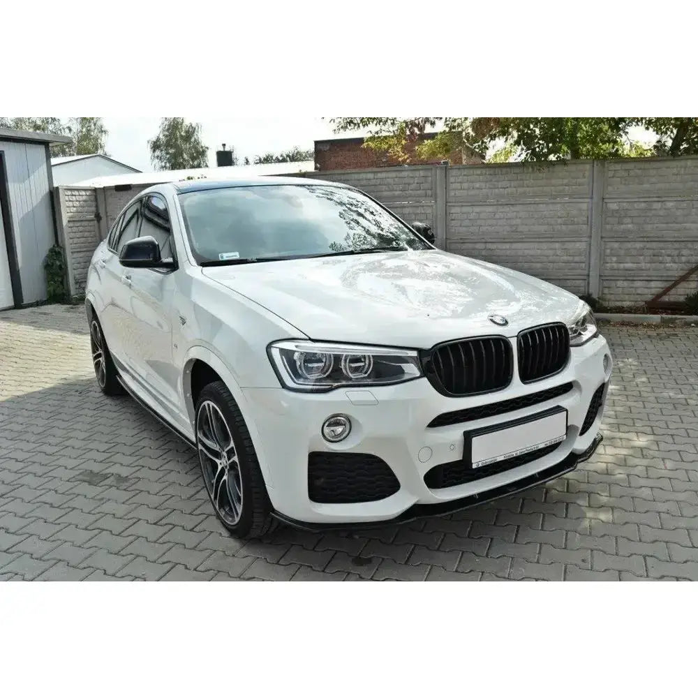 Front lip på BMW X4 M-Pack, hvit SUV med svarte detaljer og LED-frontlykter, parkert på belegningsstein.