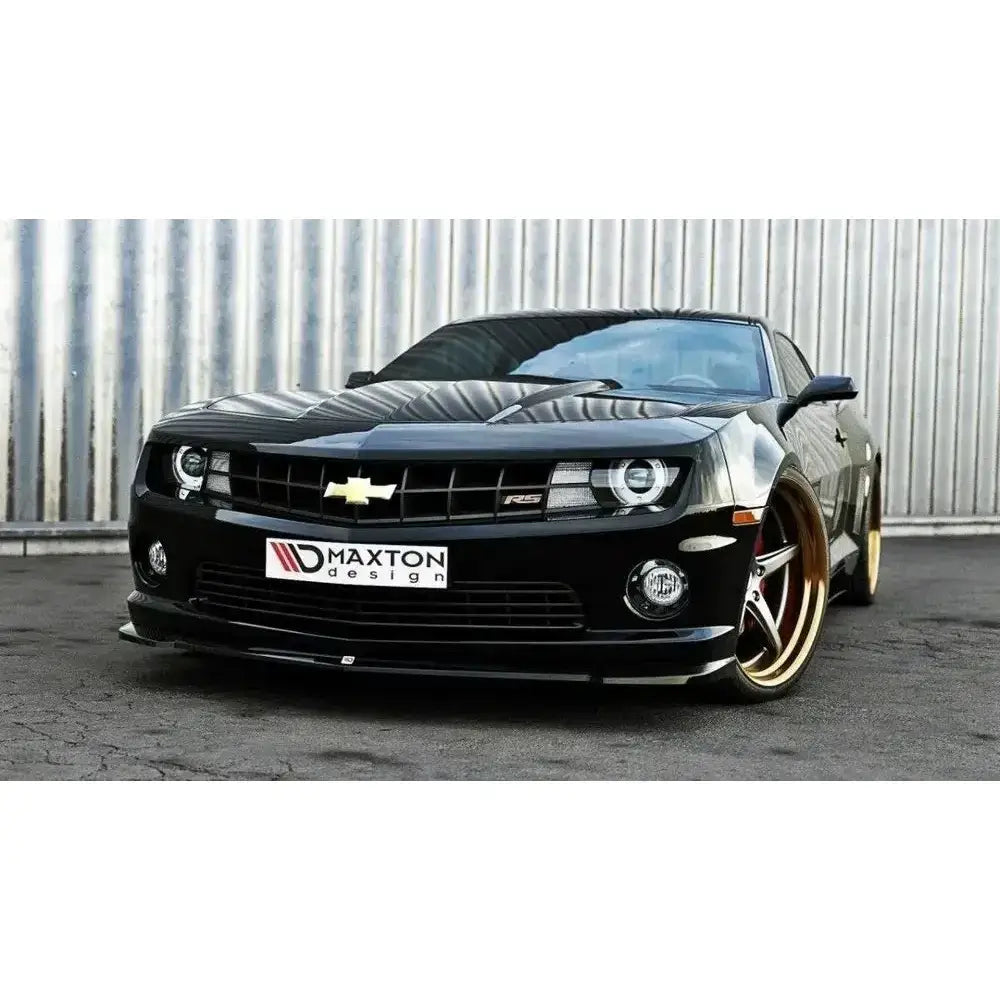 Frontspoiler Chevrolet Camaro V SS med blank svart finish og store gullfelger mot metallisk bakgrunn.