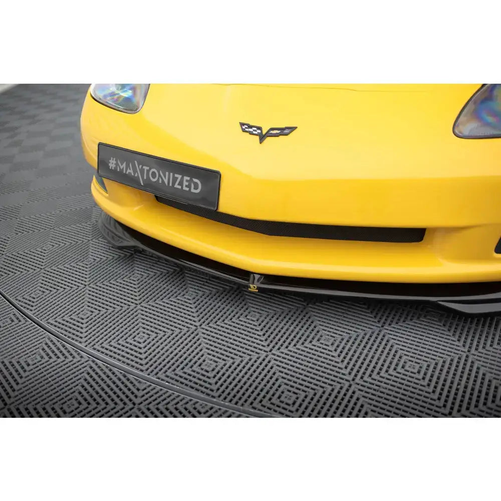 Frontsplitter på Chevrolet Corvette C6, nærbilde av sort frontleppe på gul bil med synlig logo.