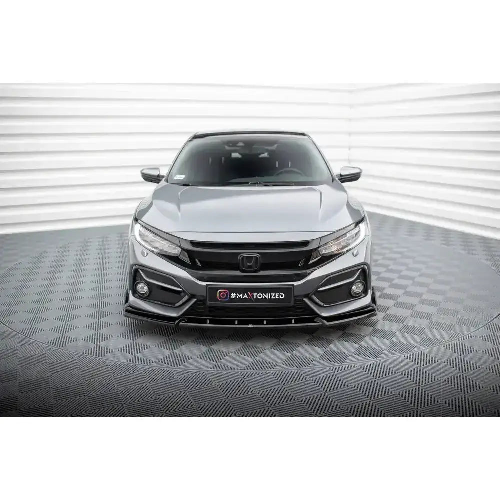 Frontspoiler på Honda Civic Sport Mk 10 med sorte detaljer sett forfra på lyst, innendørs gulv.