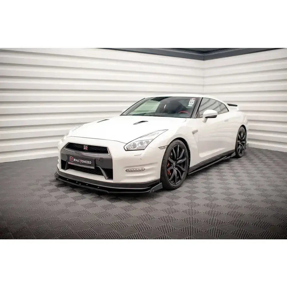 Frontsplitter på Nissan GTR R35 Facelift 11-16 med svarte felger, sett innendørs mot lyst veggpanel.