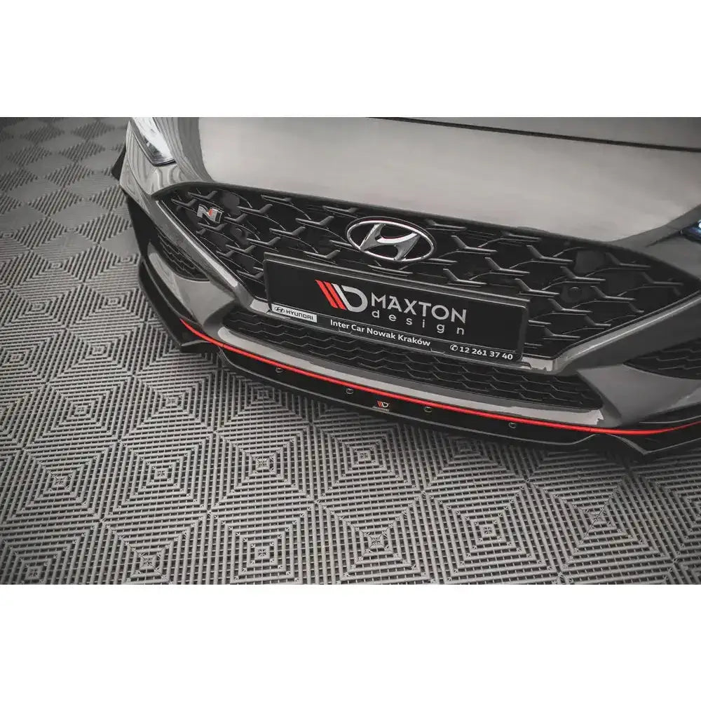 Frontsplitter til Hyundai I30 N Mk3 Facelift, sort med rød kant montert på grå bil over mønstret gulv.