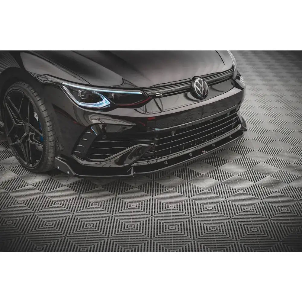 Frontspoiler på Volkswagen Golf R Mk8 med markante linjer og detaljer, sett forfra på mønstret gulv.