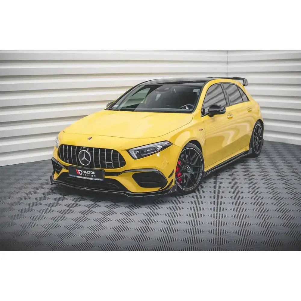 Frontspoiler på gul Mercedes-AMG A45 S med svarte felger, røde bremser og karbon-detaljer.