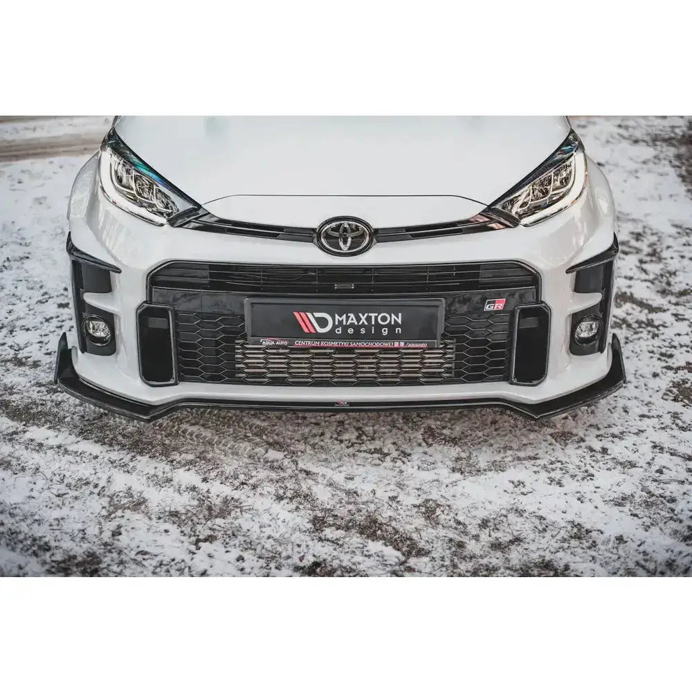 Front lip på hvit Toyota GR Yaris Mk4 med sort frontspoiler, grill og tydelige lykter på snø.