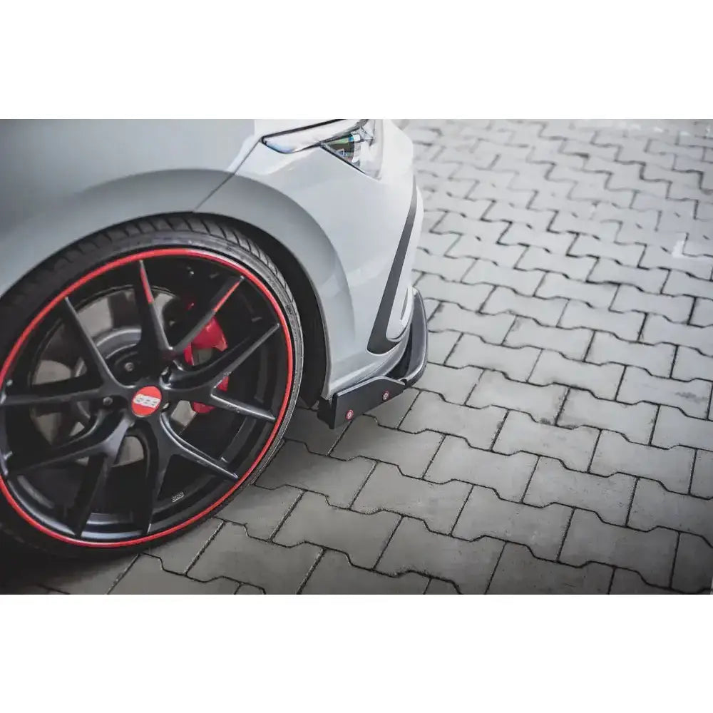 Front splitter Volkswagen Golf 8 GTI V.3 vist med sort felg, rød kant og sportsbremse på grå stein.