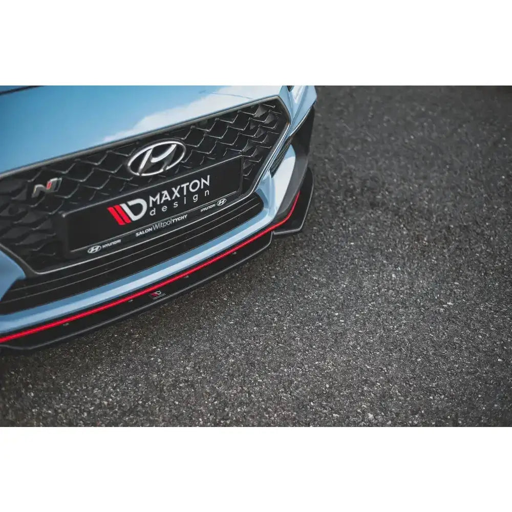 Frontsplitter på Hyundai I30 N Mk3 med sort grill og rød stripe foran, parkert på asfalt.