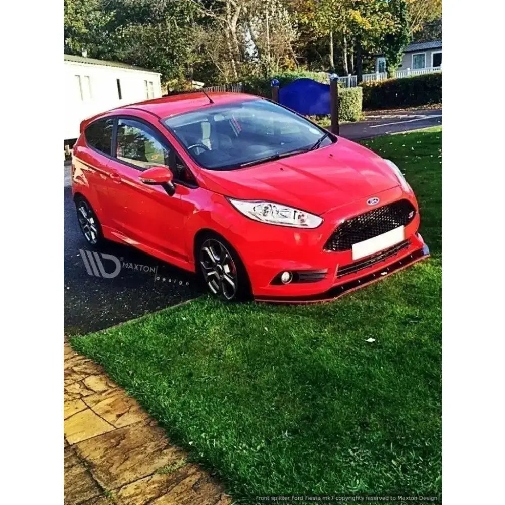 Frontleppe på Ford Fiesta Mk7 ST Facelift 2013-2016, rød bil med svart spoiler parkert på gress.