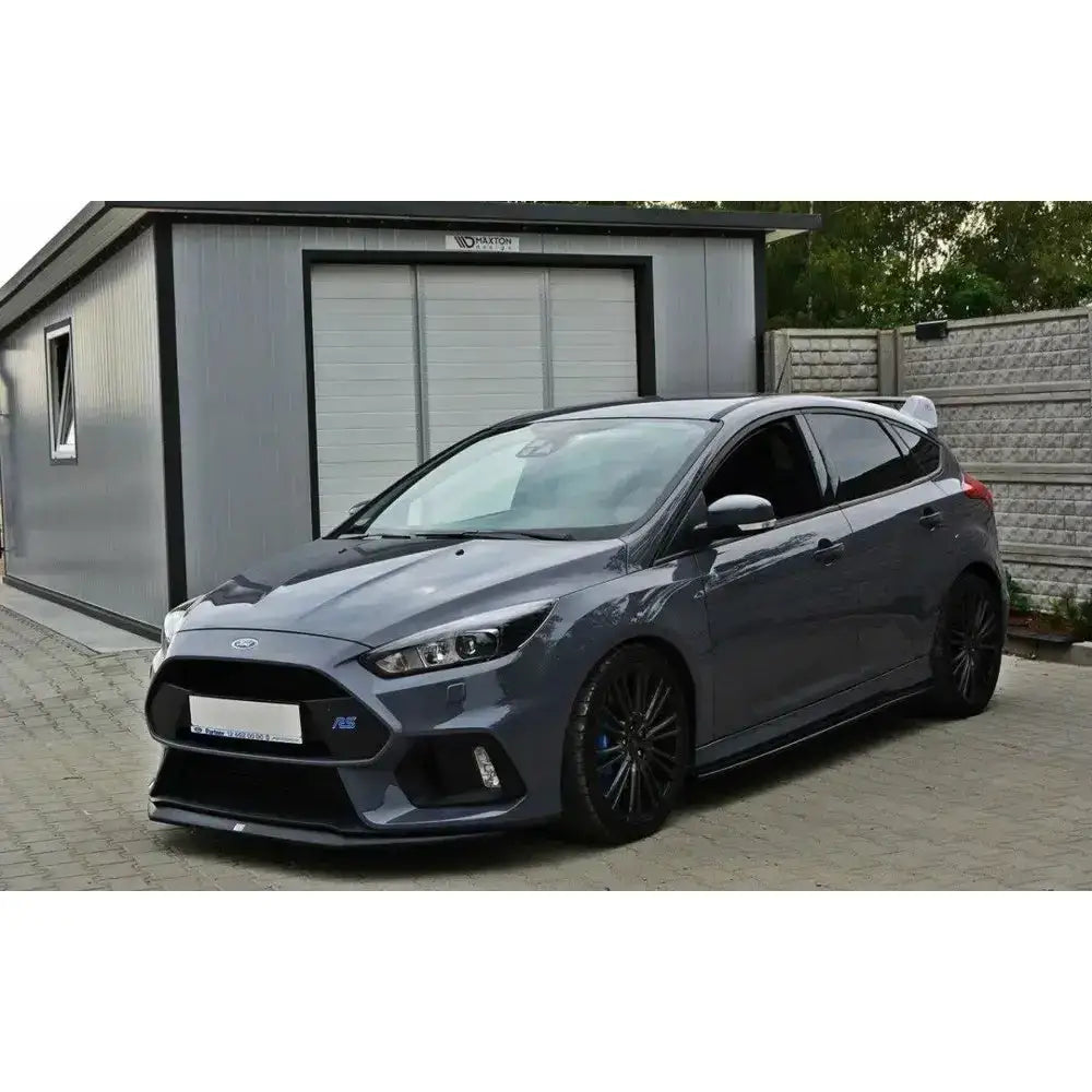 Frontspoiler på Ford Focus 3 RS V.2, grå bil med svarte felger og synlig bakspoiler foran garasje.