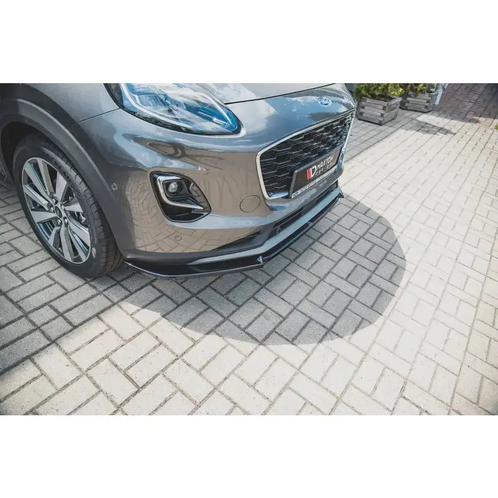Frontsplitter til Ford Puma, sort spoiler montert under grillen, fotografert skrått forfra på brostein.