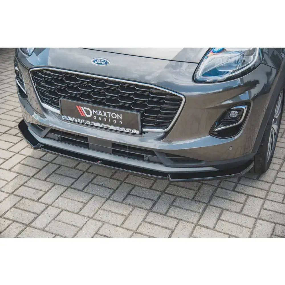 Front splitter på sort frontleppe til Ford Puma montert under grå støtfanger, sett fra skrå vinkel foran.