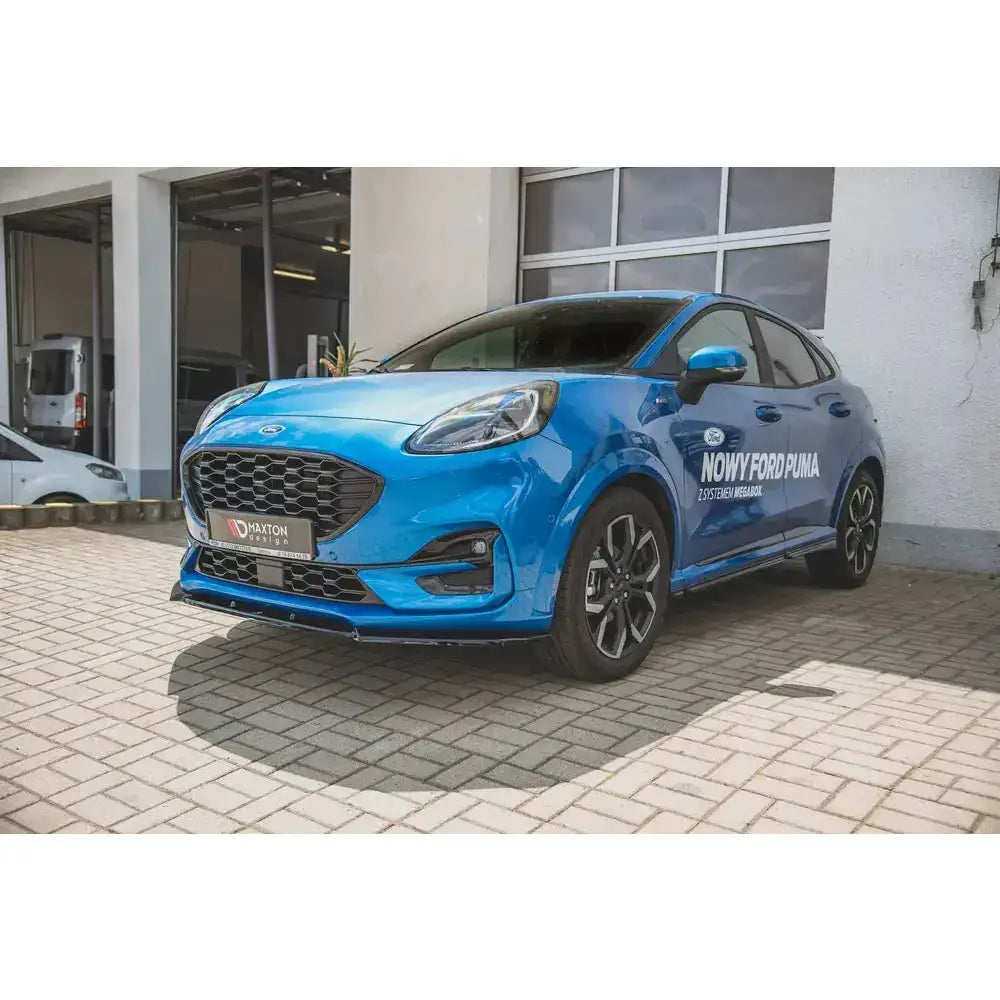 Front lip på Ford Puma St-Line, blå bil med sorte felger og stor grill foran verkstedbygning.