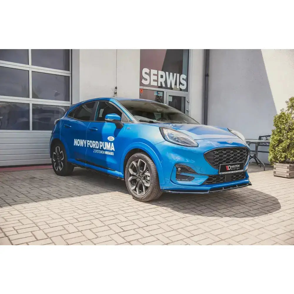 Frontleppe Ford Puma St-Line på blå bil med sorte detaljer parkert foran bygning med "SERWIS"-skilt.