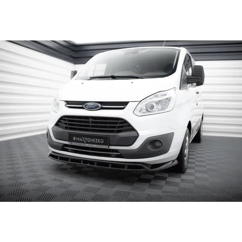 Frontspoiler til Ford Transit Custom Mk1 på hvit varebil med sorte detaljer sett forfra fra skrå vinkel.