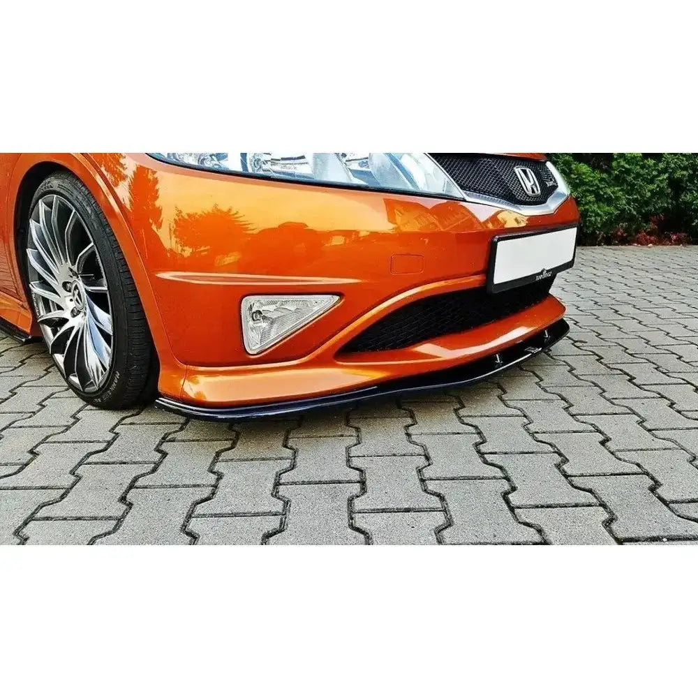 Frontsplitter på Honda Civic VIII Type S/R, sort mot oransje front, lav vinkel, sølvfelger og belegningsstein.