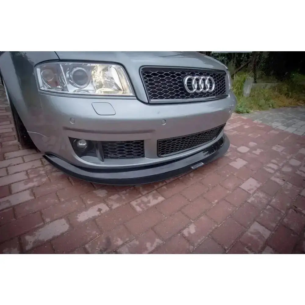 Frontsplitter på grå Audi RS6 C5 med sort grill, nærbilde parkert på brostein.