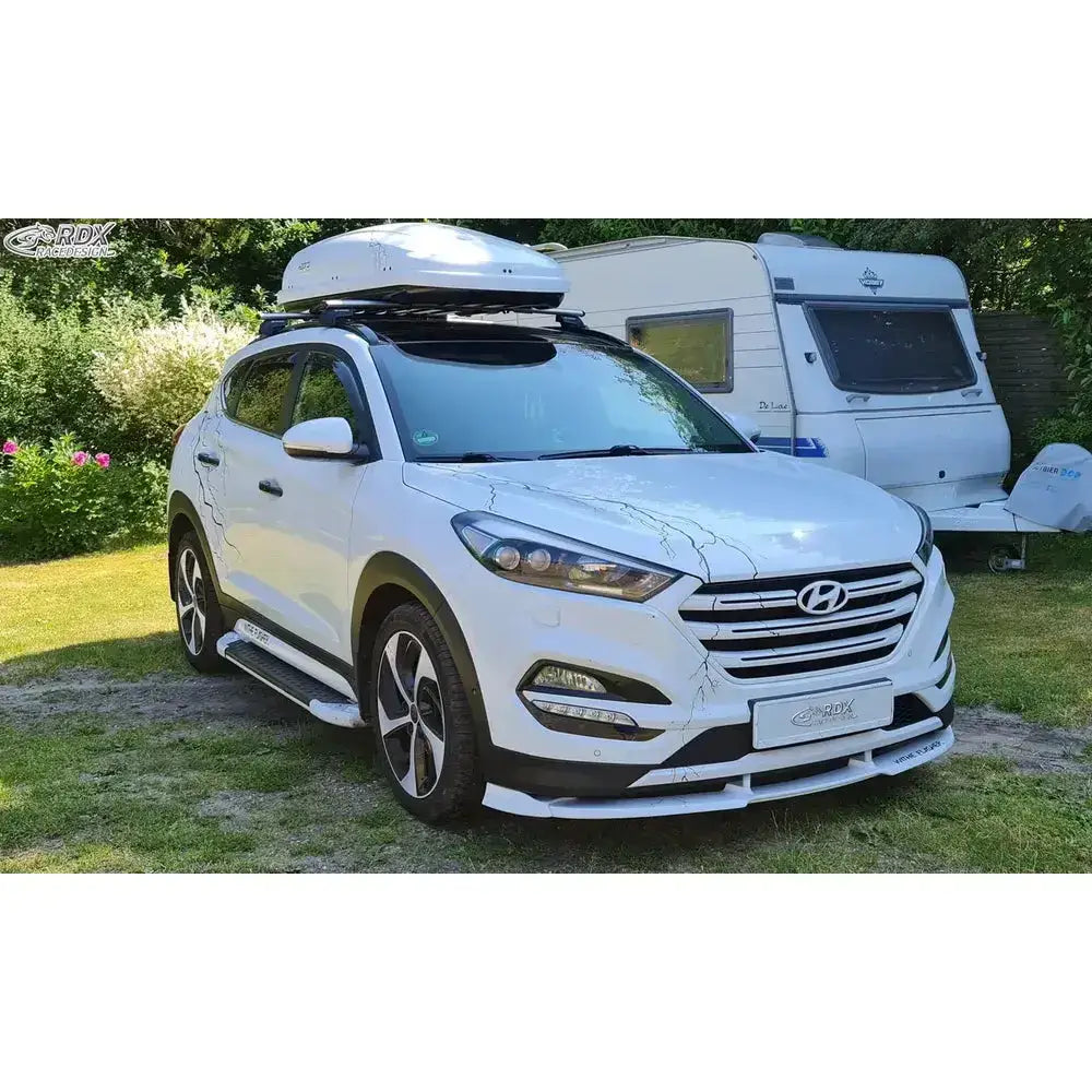 Frontspoiler på hvit Hyundai Tucson TL 15-18 med takboks, sorte detaljer og stigtrinn, parkert ute.