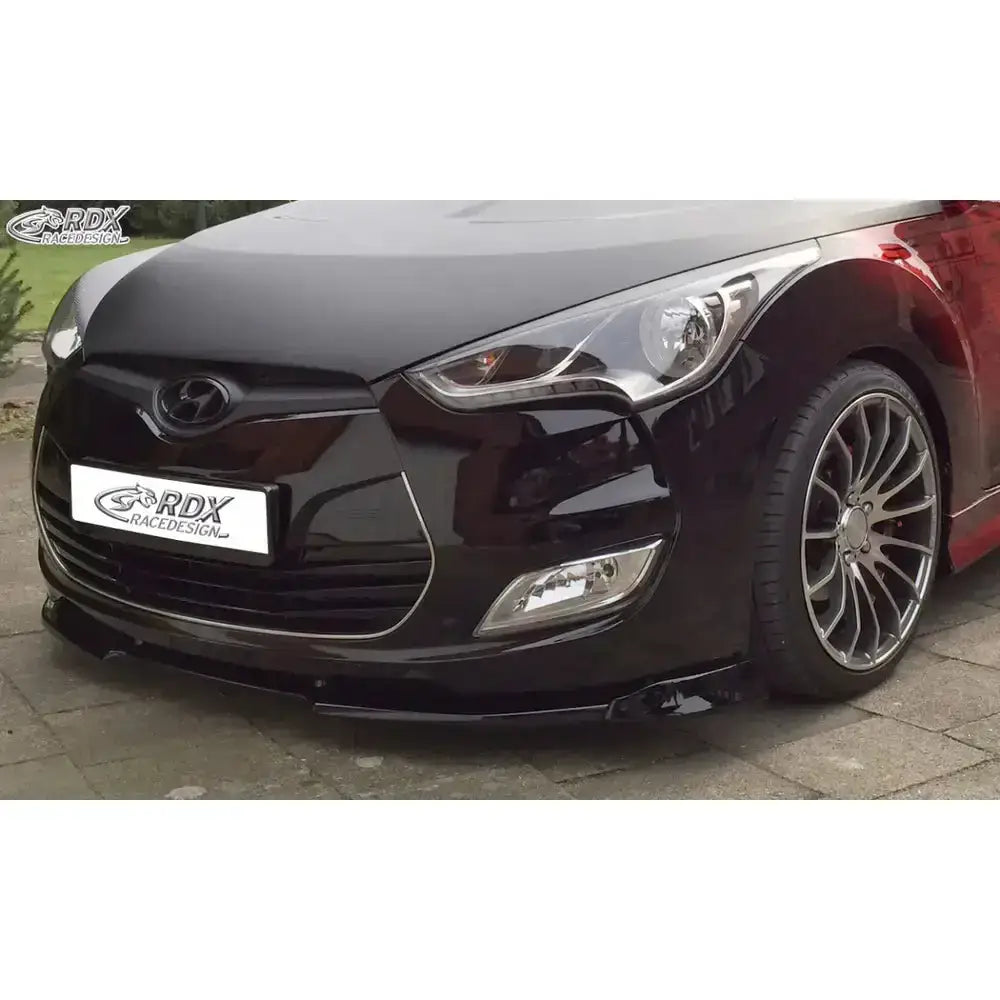 Front lip til Hyundai Veloster 11-17 i sort plast, montert på bil med aluminiumsfelger og frontlys.