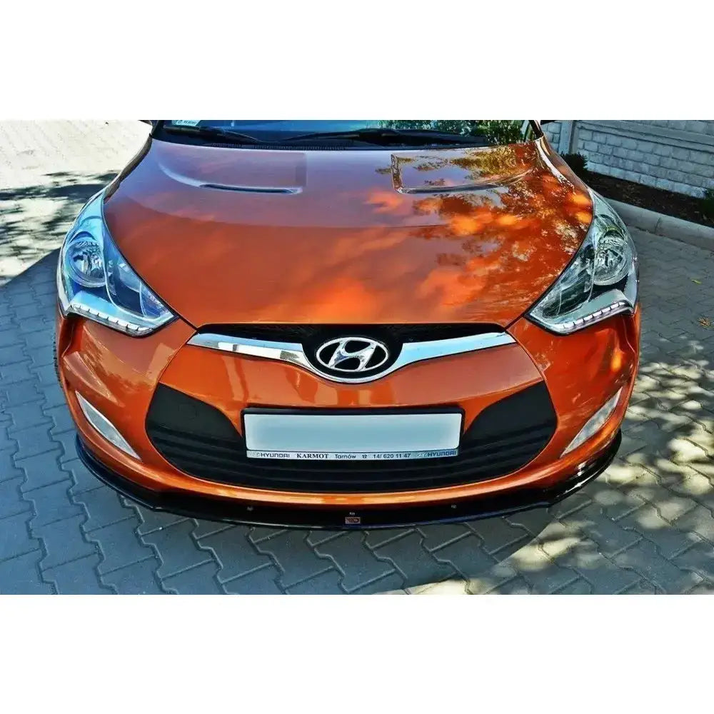 Front lip Hyundai Veloster i oransje med sølv grill og svart underdel, sett forfra på brostein.