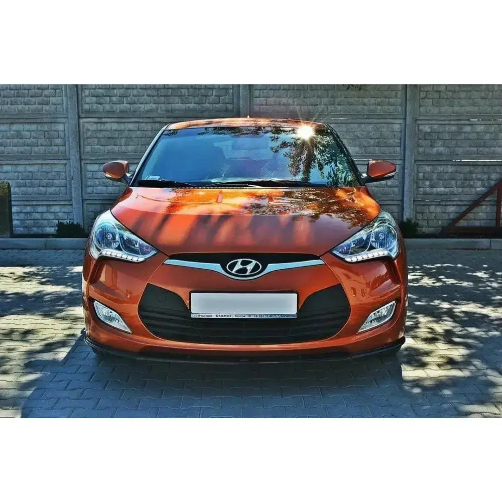 Front splitter på Hyundai Veloster med oransje lakk, LED-lys og kromdetaljer foran betonggjerde.