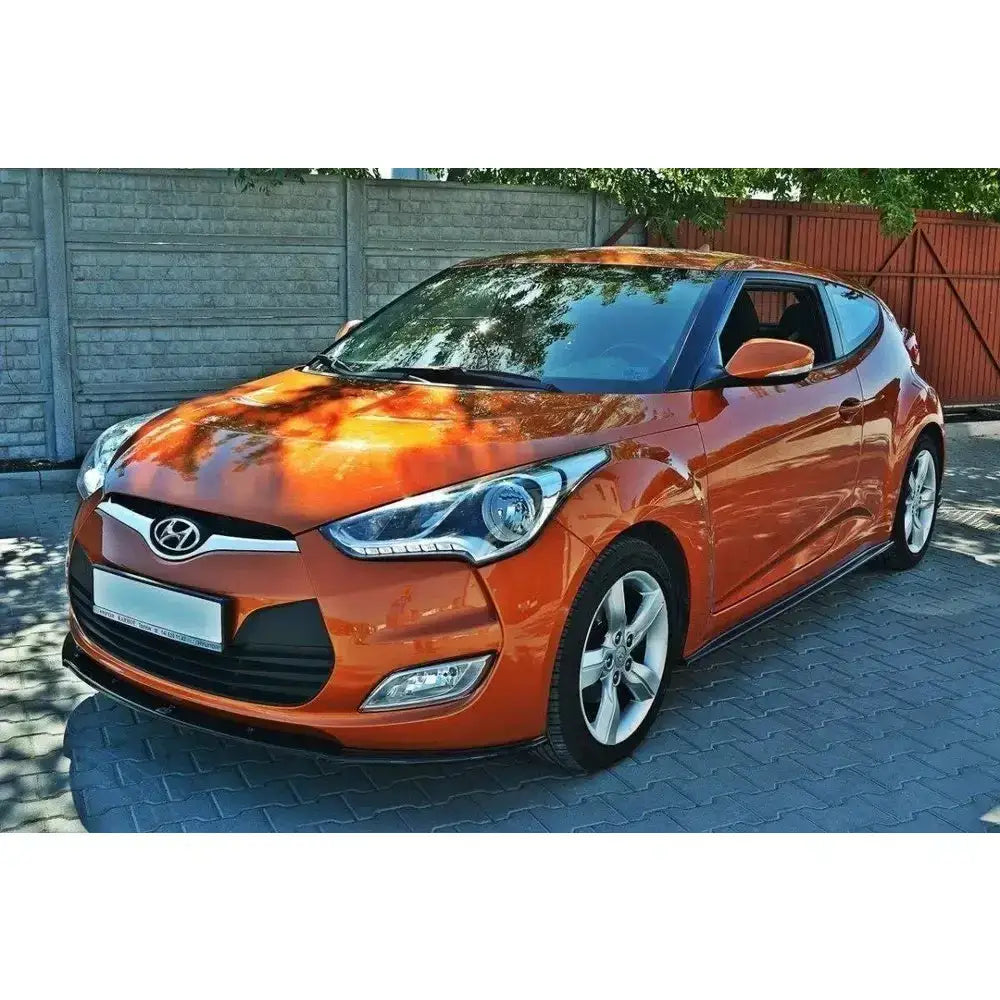 Frontleppe Hyundai Veloster oransje med sorte detaljer og fem-eikers felger sett fra skrå vinkel.