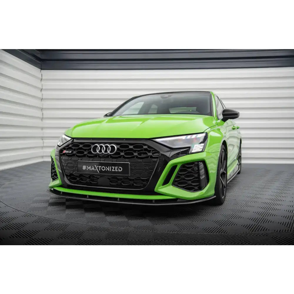 Frontspoiler på grønn Audi RS3 8Y med sort grill og karbon detaljer, sett forfra i lyst rom.