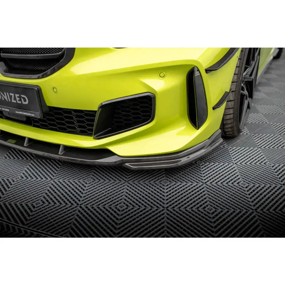 Frontspoiler i karbon til BMW 1 F40 M-Pack vises på gulgrønn bil med sorte luftinntak.