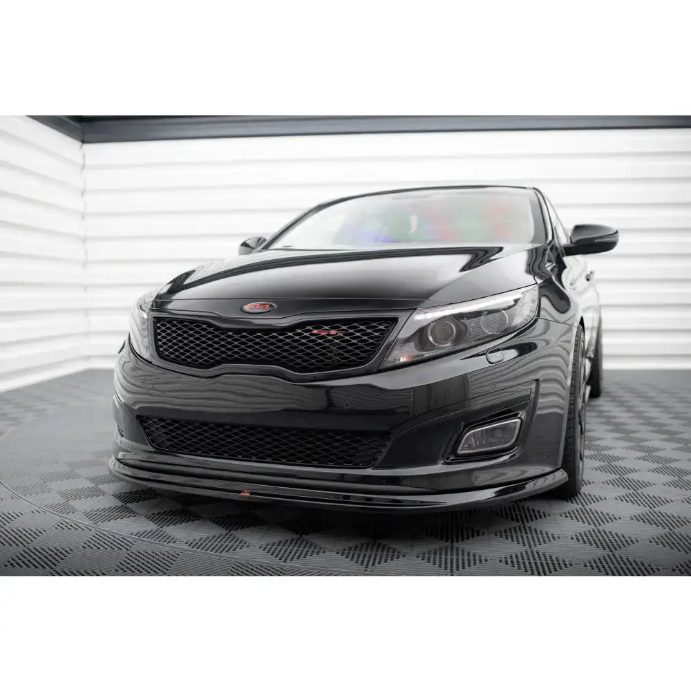 Frontspoiler på Kia Optima Mk3 med sportslig frontfanger og rød logo, sett forfra i lyst rom.