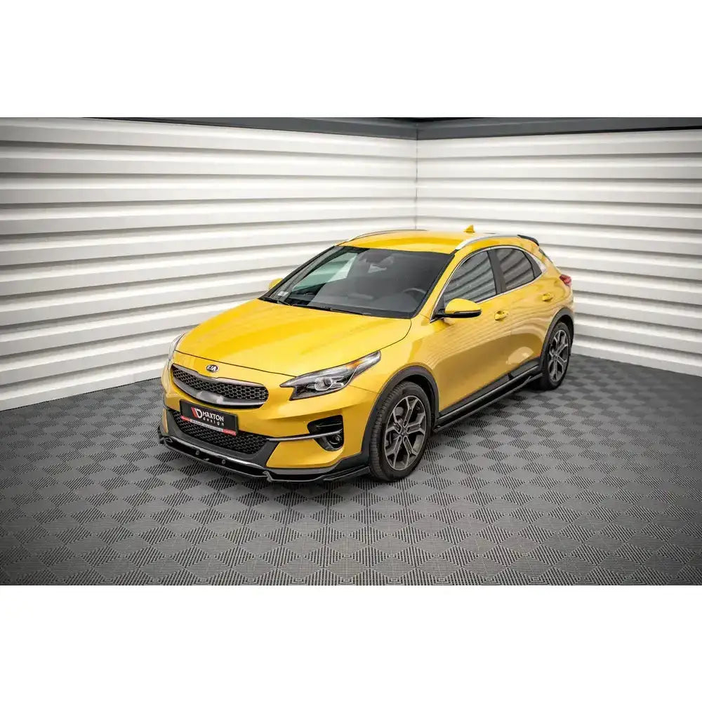 Frontsplitter på gul Kia XCeed Mk1 2019-modell med svarte detaljer og aluminiumsfelger innendørs.