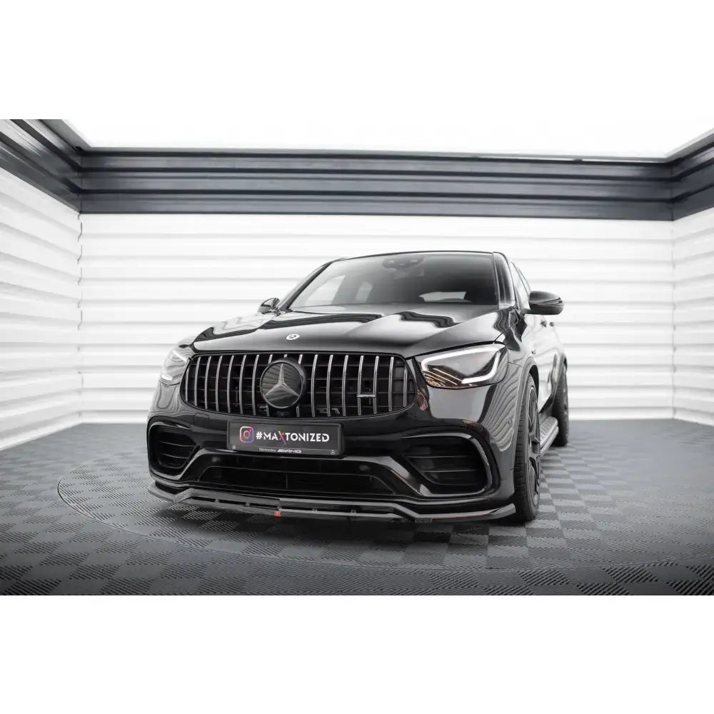 Frontspoiler på Mercedes-AMG GLC 63 SUV med store luftinntak og markant grill i lyst studio.