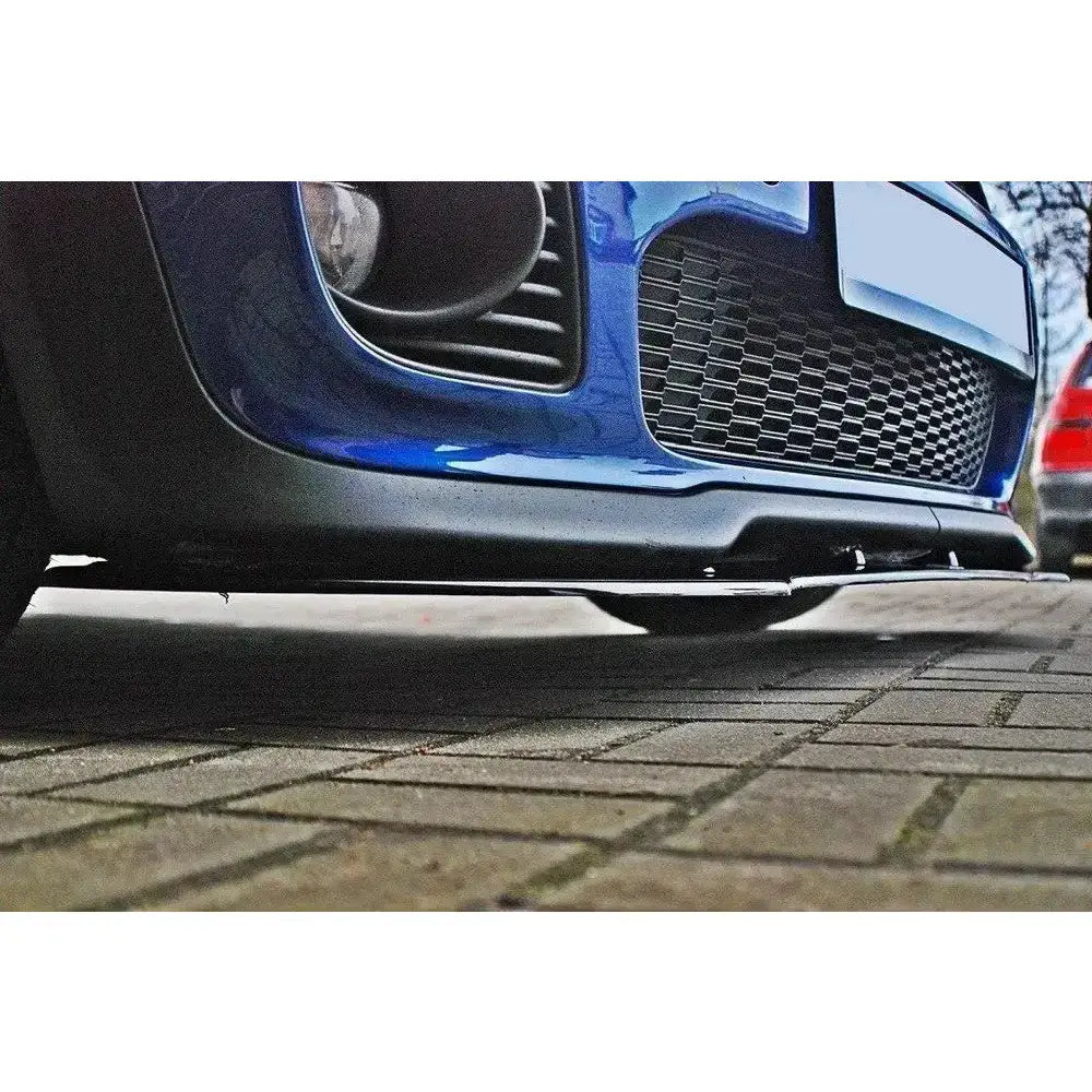 Frontspoiler til Mini Cooper R56 Jcw i svart plast, detaljert med riller og blå frontfanger.