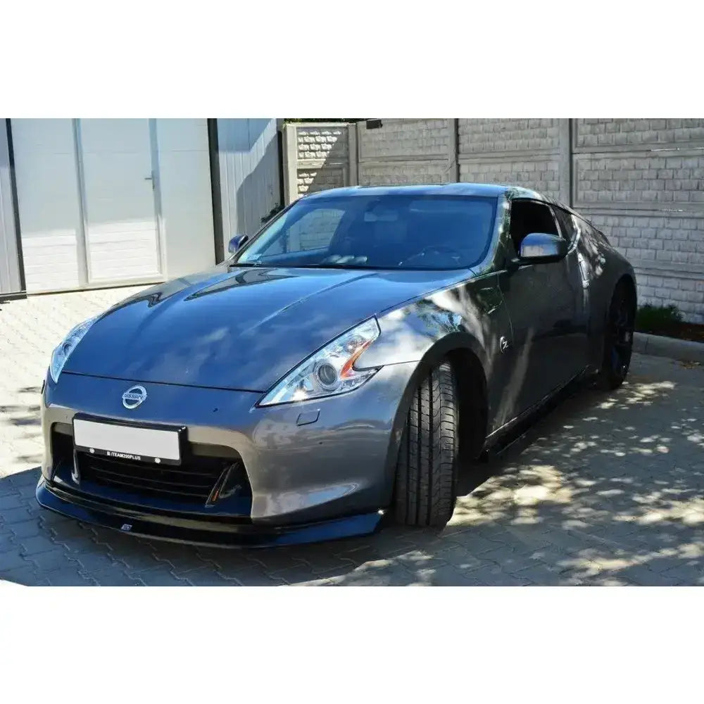 Front lip på Nissan 370Z grå sportsbil med lav spoiler parkert på steinlagt underlag.