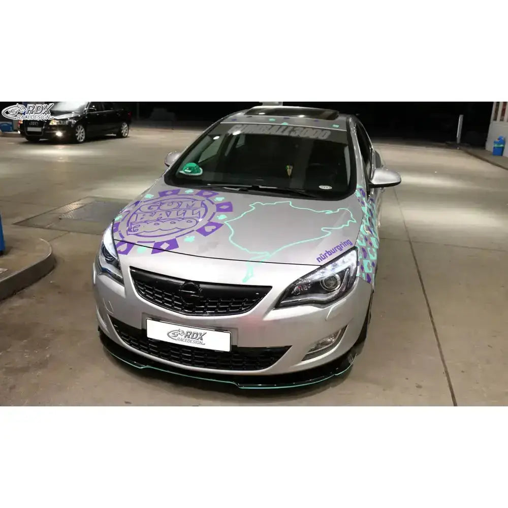 Frontspoiler Opel Astra J 09-12 sett forfra med lilla og turkise Nürburgring-klistremerker på panseret.