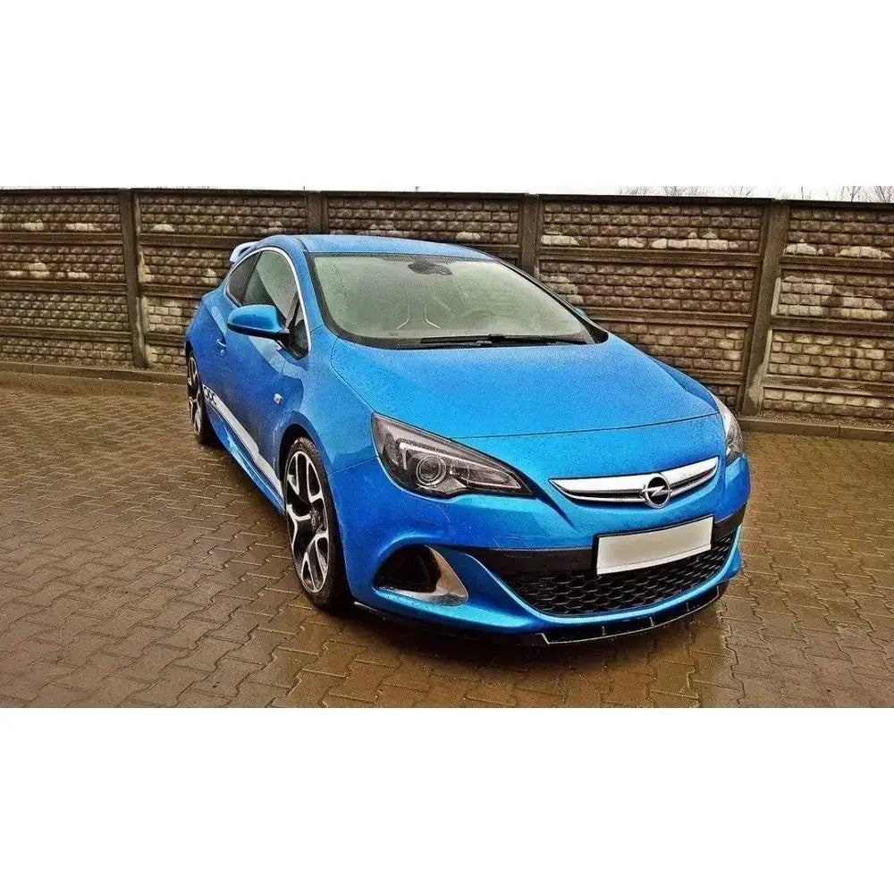 Frontspoiler Opel Astra J Opc Vxr i metallic blått, sett skrått forfra på brosteinsbelagt plass.