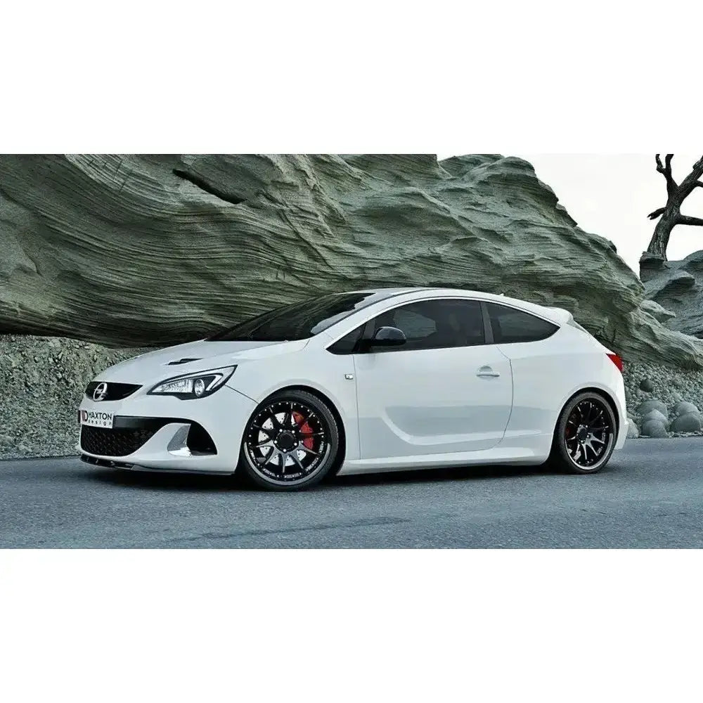 Front lip på hvit Opel Astra J OPC med sorte felger, røde bremsecalipere og tonede ruter utendørs.