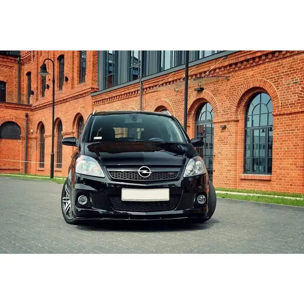 Front splitter på Opel Zafira B OPC med blank svart lakk, sett forfra foran teglsteinsbygning.