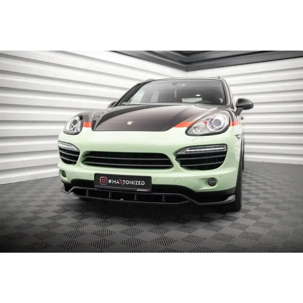 Frontsplitter på Porsche Cayenne Mk2 med lysegrønn lakk, sort panser og oransje detaljer, innendørs.