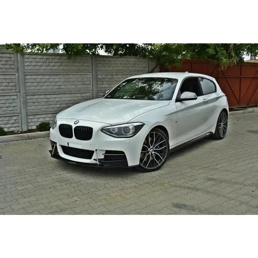 Front lip på hvit BMW 1 F20/F21 M-Power med sorte felger og lav frontspoiler, sett skrått forfra.